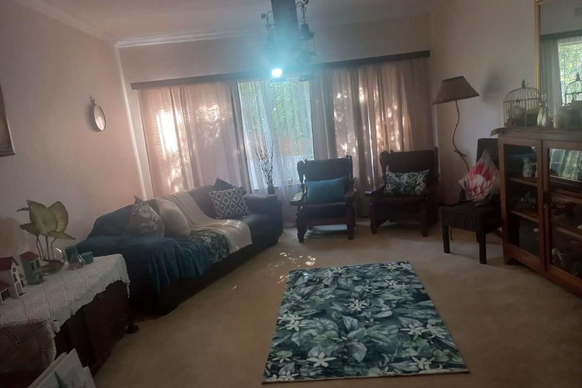 A living room featuring carpeted flooring, coving, and large windows with curtain rails, offering a comfortable and traditional living space.