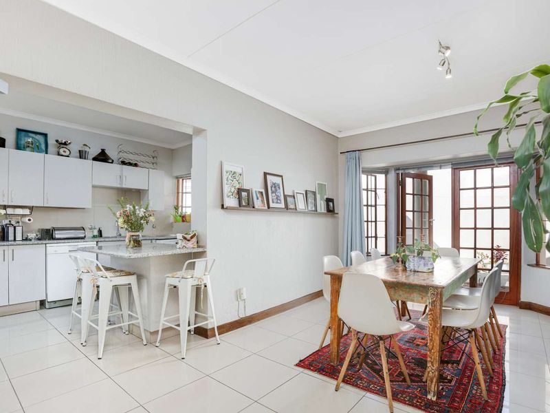 Open-plan kitchen and dining area featuring tiled floors, granite countertops, and direct access to the outdoors through classic french doors.