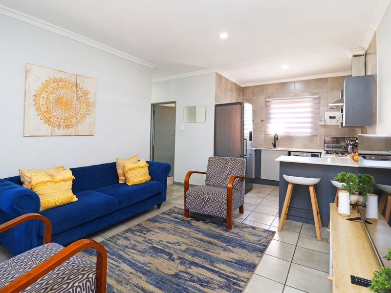 An open-plan living area featuring a modern kitchen with built-in cabinetry, a breakfast island, and tiled flooring throughout the combined space.