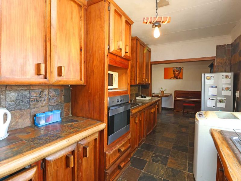 A dated kitchen featuring extensive wooden cabinetry, slate tile countertops, and matching slate flooring, offering a rustic aesthetic with built-in oven and microwave.