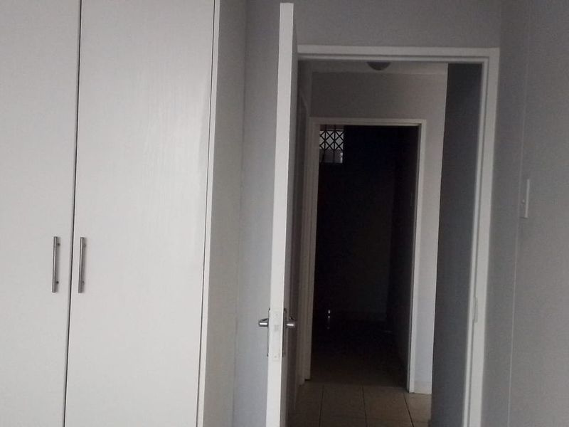 A bedroom interior featuring built-in cupboards and a doorway leading to a hallway.