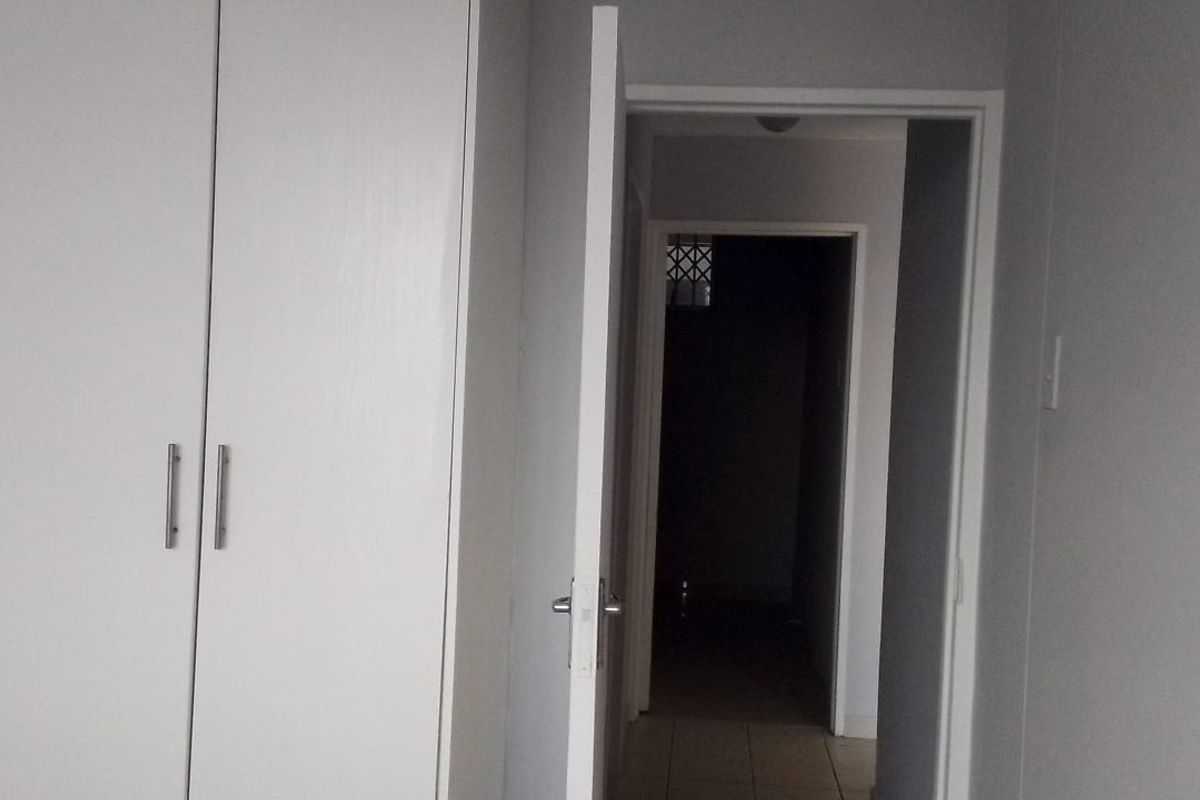 A bedroom interior featuring built-in cupboards and a doorway leading to a hallway.