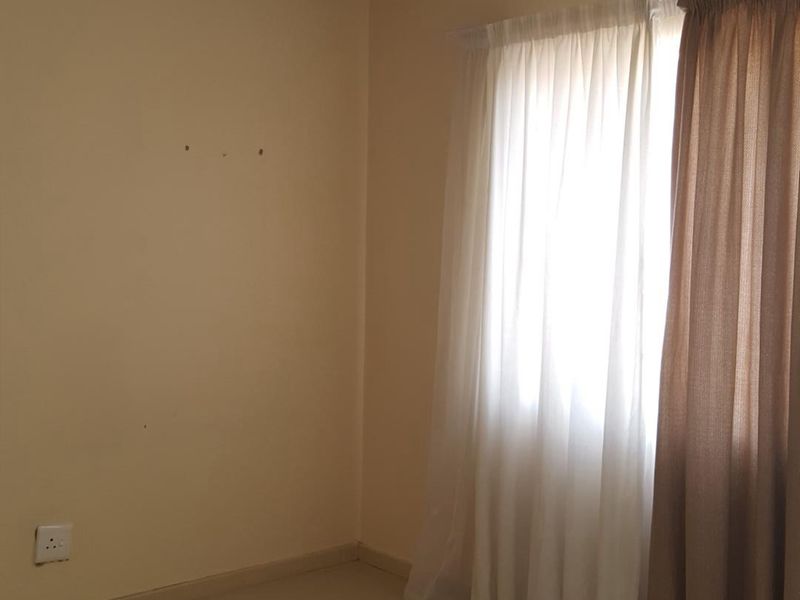 An empty bedroom featuring neutral wall paint, carpeted flooring, and a ceiling-mounted light fixture, ready for personalization.