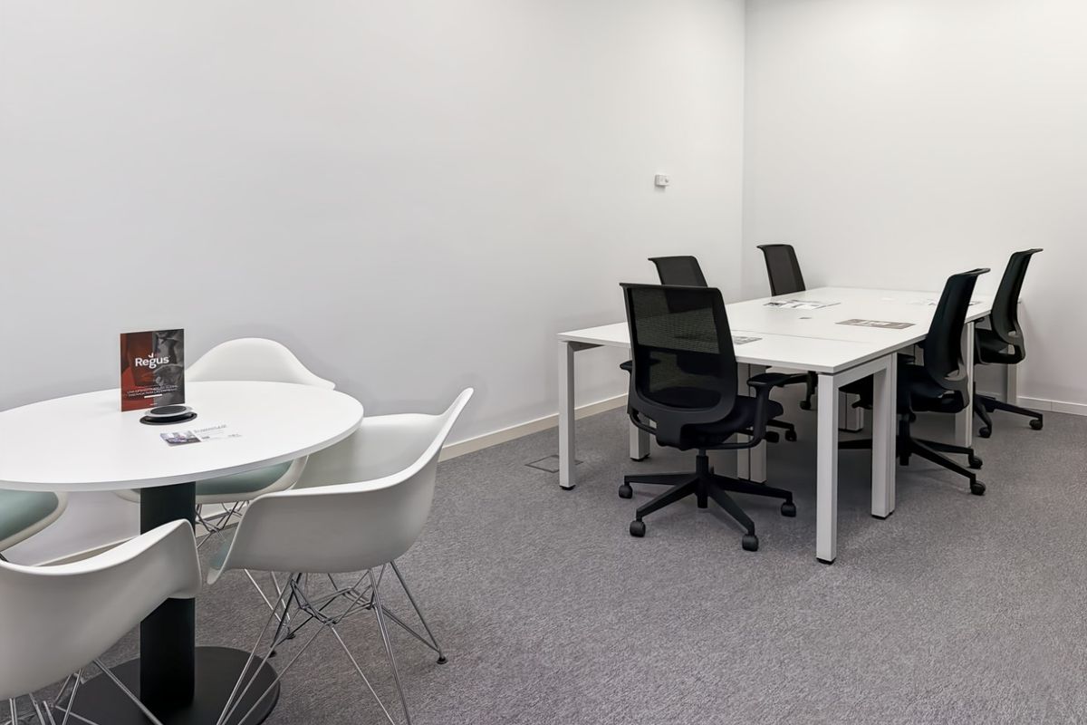 A clean, modern office space featuring neutral walls, carpeted flooring, and recessed ceiling lighting, suitable for professional meetings or collaborative work.