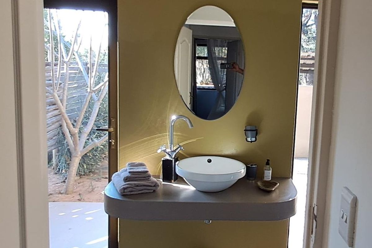 A compact bathroom featuring a modern vessel sink mounted on a concrete-style vanity, with direct access to an outdoor area.