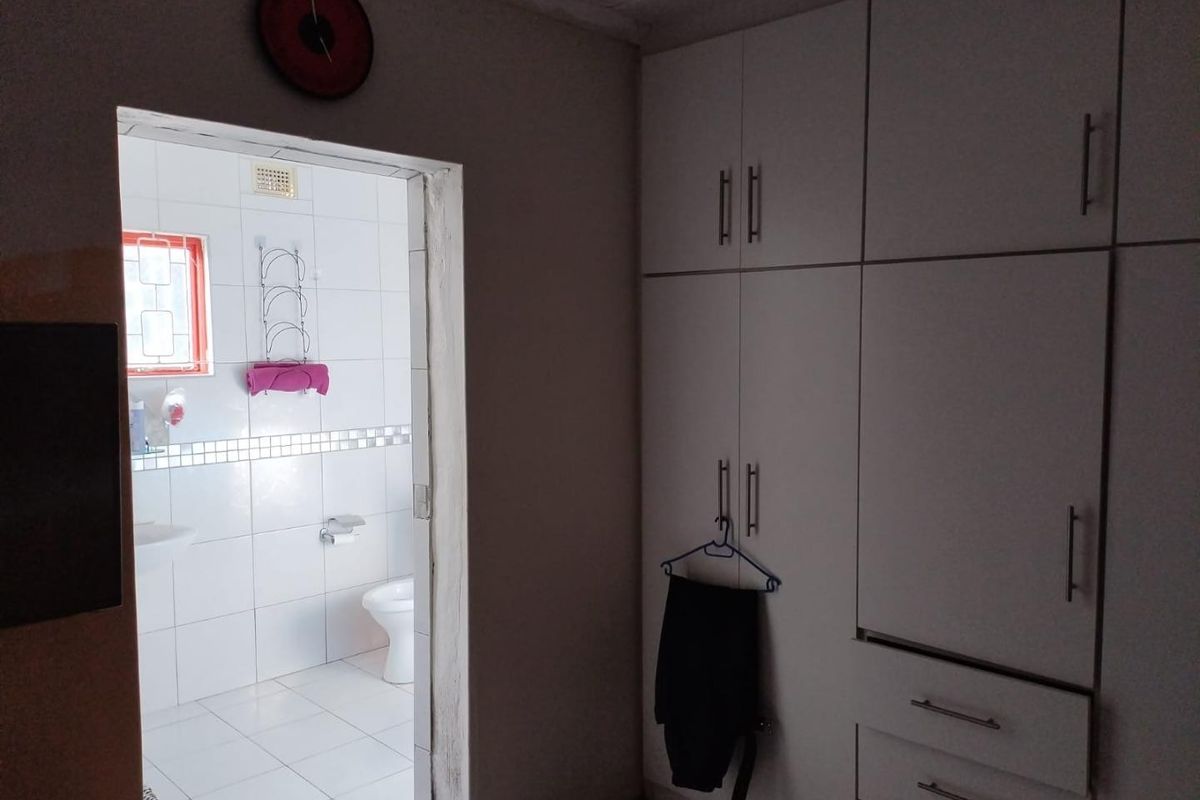 Bedroom featuring built-in cupboards and direct access to an en-suite bathroom with tiled finishes.