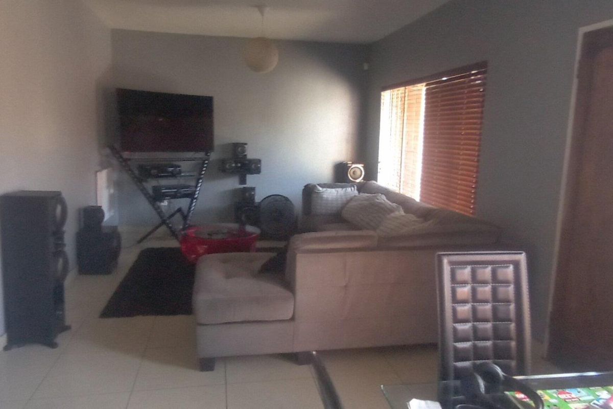 A living room area featuring tiled flooring and wooden window blinds, providing a functional space for relaxation.