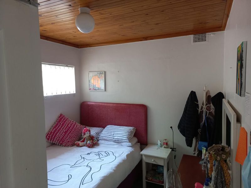 A compact bedroom featuring a timber tongue and groove ceiling and a functional ventilation grille.