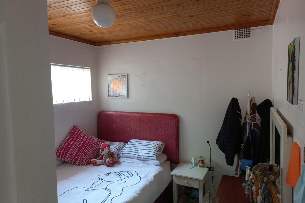 A compact bedroom featuring a timber tongue and groove ceiling and a functional ventilation grille.