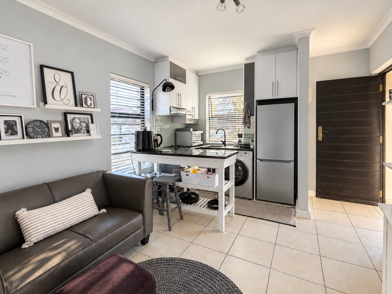 An open-plan living and kitchen area featuring tiled flooring, built-in cabinetry, and a functional kitchen layout with integrated appliances.
