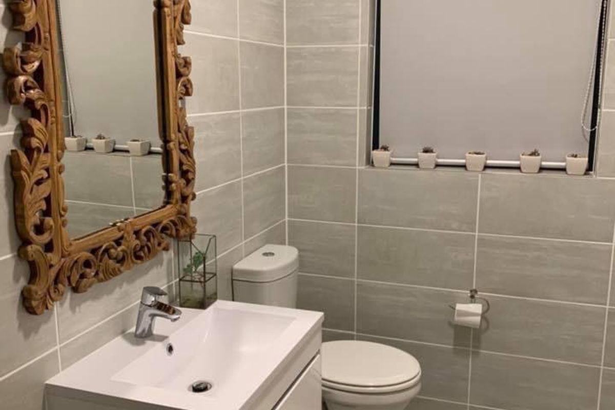 Modern bathroom featuring a wall-mounted vanity, ceramic basin, close-coupled toilet, and neutral grey wall and floor tiling.