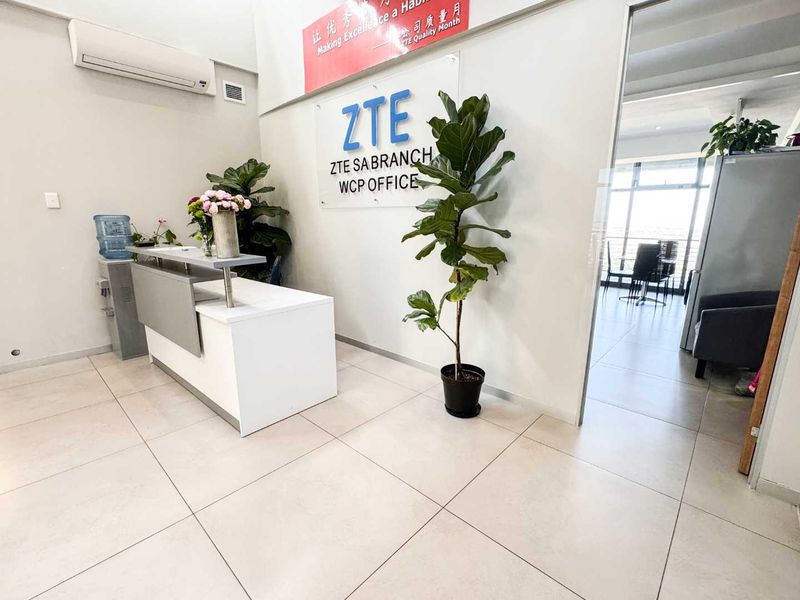 Professional office reception area featuring a modern reception desk, tiled flooring, and a glass partition leading into the main office space.