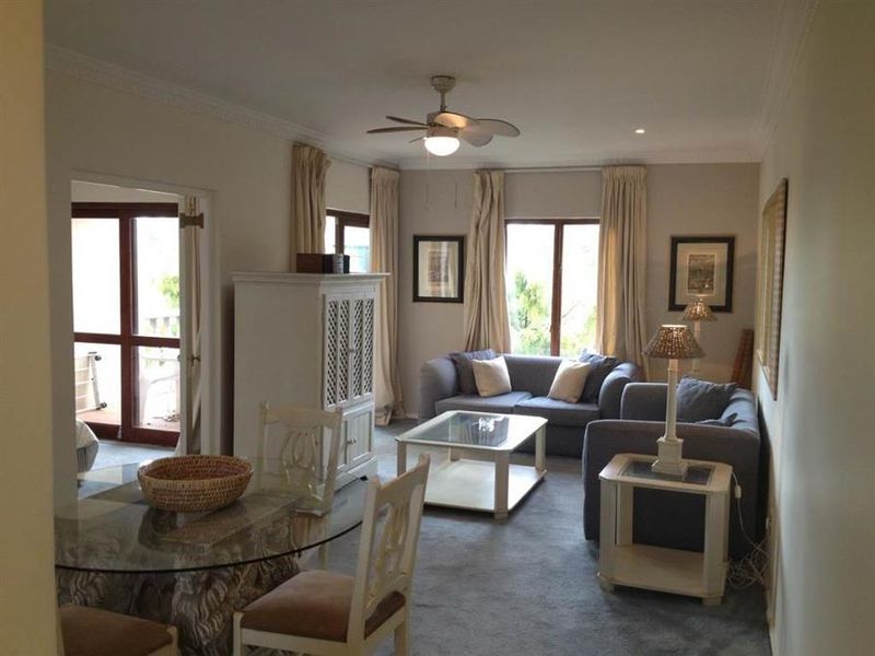 Open plan living and dining area featuring neutral wall tones, crown molding, a ceiling fan, and direct access to an outdoor balcony space.