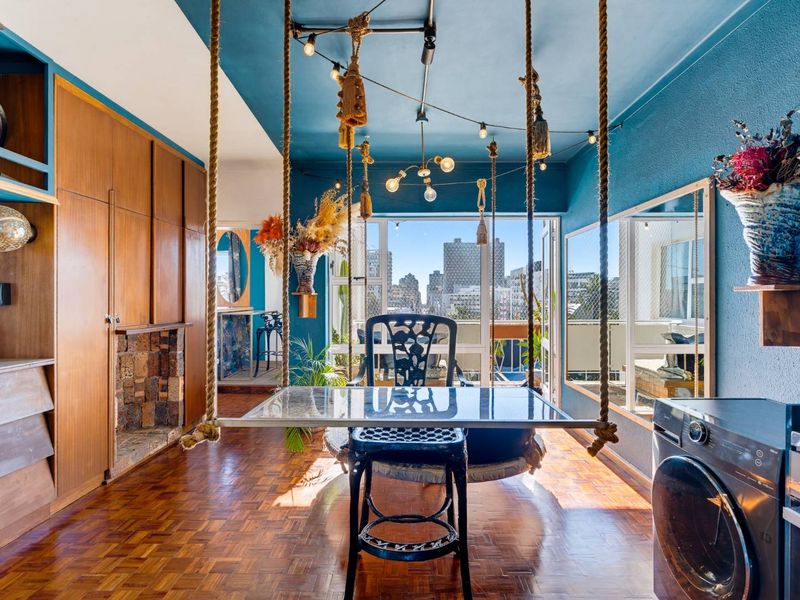 Open-plan living area featuring parquet flooring, built-in cabinetry, a stone fireplace, and integrated appliances, with direct access to a balcony and city views.