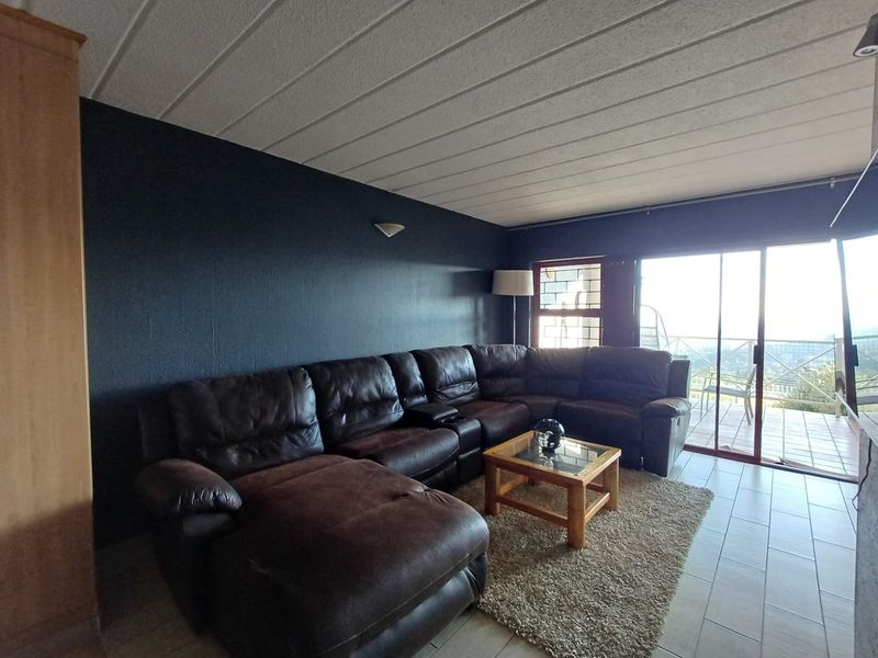 A living room featuring tiled flooring, a textured ceiling, and large sliding glass doors leading to an outdoor balcony area.