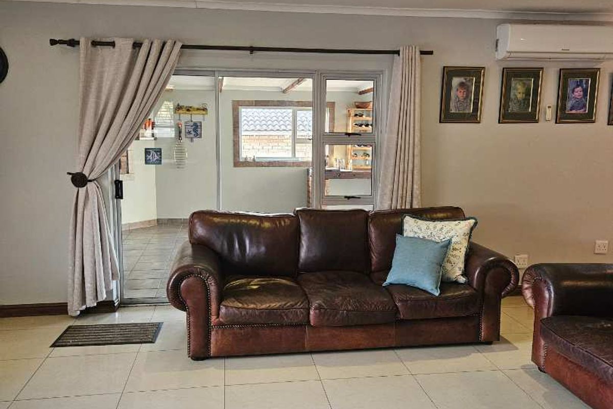 Spacious living room featuring large format floor tiles, recessed lighting, and a wall-mounted air conditioning unit, with direct access to an outdoor patio area.
