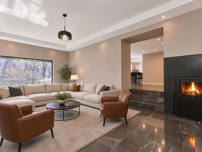 Spacious living room featuring polished stone flooring, a modern built-in fireplace, recessed lighting, and a large picture window overlooking the garden.