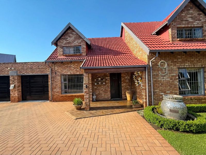 A well-maintained face brick family home featuring a tiled roof, paved driveway, integrated garage, and a welcoming covered entrance porch.