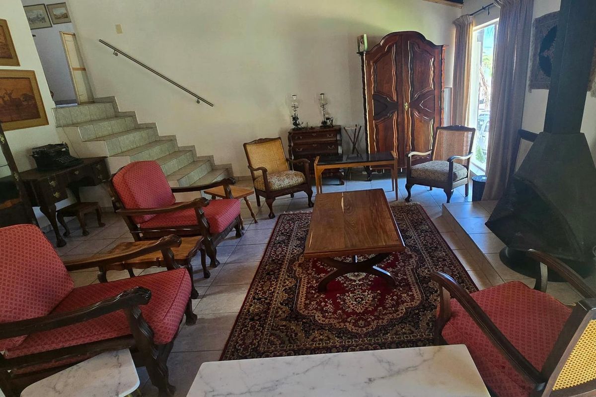 A living room featuring a freestanding fireplace, tiled flooring, and a staircase with a metal handrail.