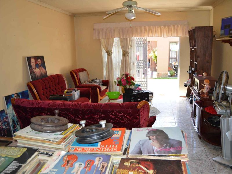 A living room featuring tiled flooring, a ceiling fan, and a sliding glass door providing access to an outdoor area.