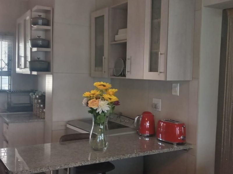 A functional kitchen featuring granite countertops, built-in cabinetry, and a stainless steel sink with a window security gate.
