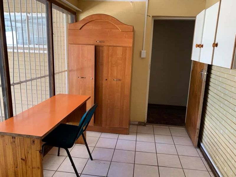 A bedroom featuring tiled flooring, built-in cabinetry, and a sliding glass door with security bars, requiring cosmetic updates to the walls.