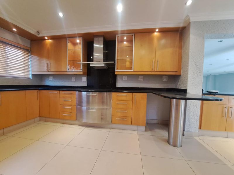 A well-maintained kitchen featuring wooden cabinetry, granite countertops, stainless steel appliances, and a breakfast bar with tiled flooring.