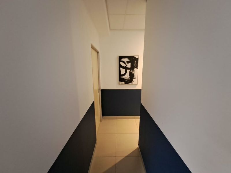 A clean, well-maintained office hallway featuring neutral tiled flooring and a modern two-tone wall finish.
