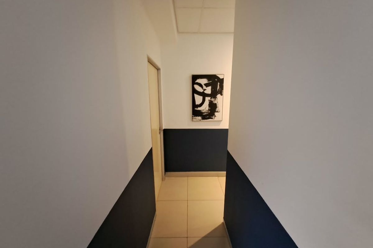 A clean, well-maintained office hallway featuring neutral tiled flooring and a modern two-tone wall finish.