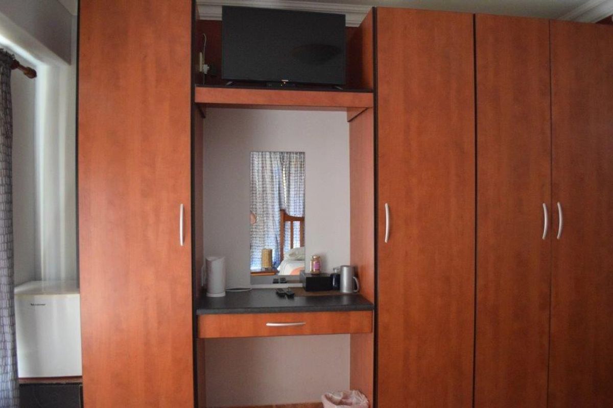 A bedroom featuring built-in wooden cabinetry with an integrated vanity desk and storage space.