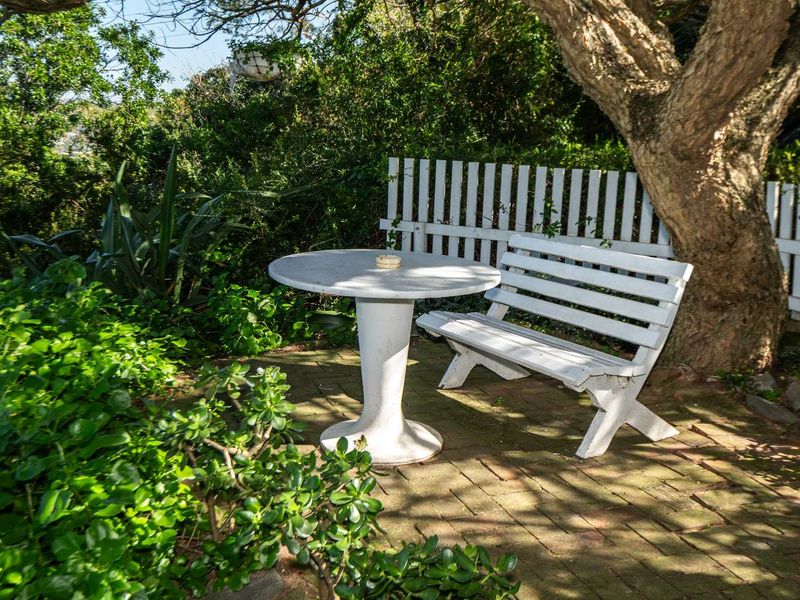 A peaceful garden setting featuring brick paving nestled under mature trees, providing a quiet outdoor retreat.