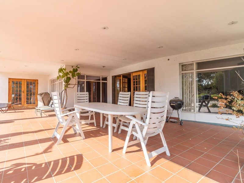 Spacious covered patio featuring terracotta tiling, recessed lighting, and multiple access points to the interior through sliding and french doors.