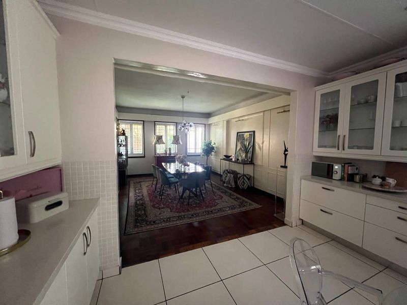 Open plan kitchen and dining area featuring a blend of tiled and parquet flooring, built-in cabinetry, and classic crown molding details.