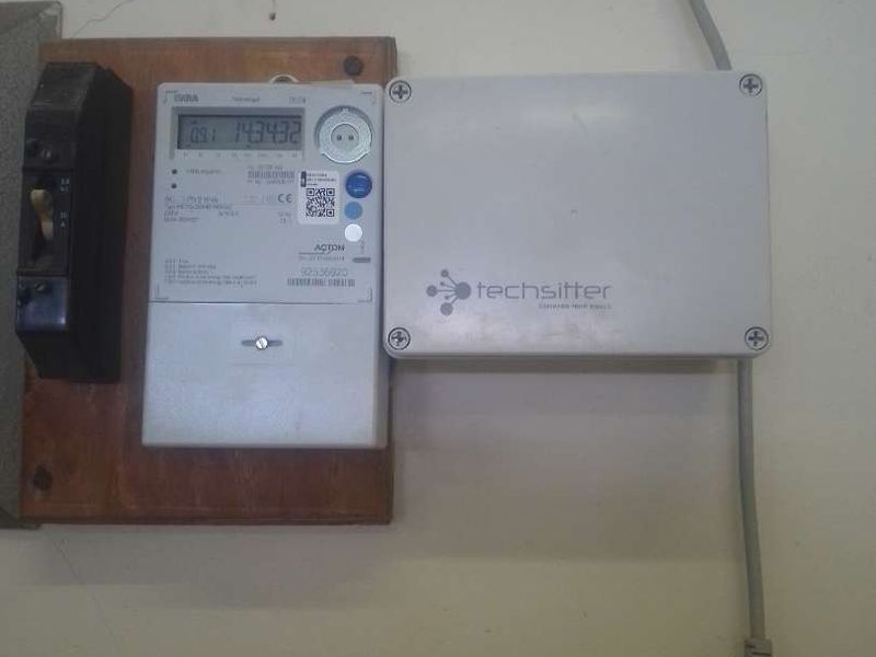 Wall-mounted electricity meter and associated utility control equipment installed on a wooden backing board.