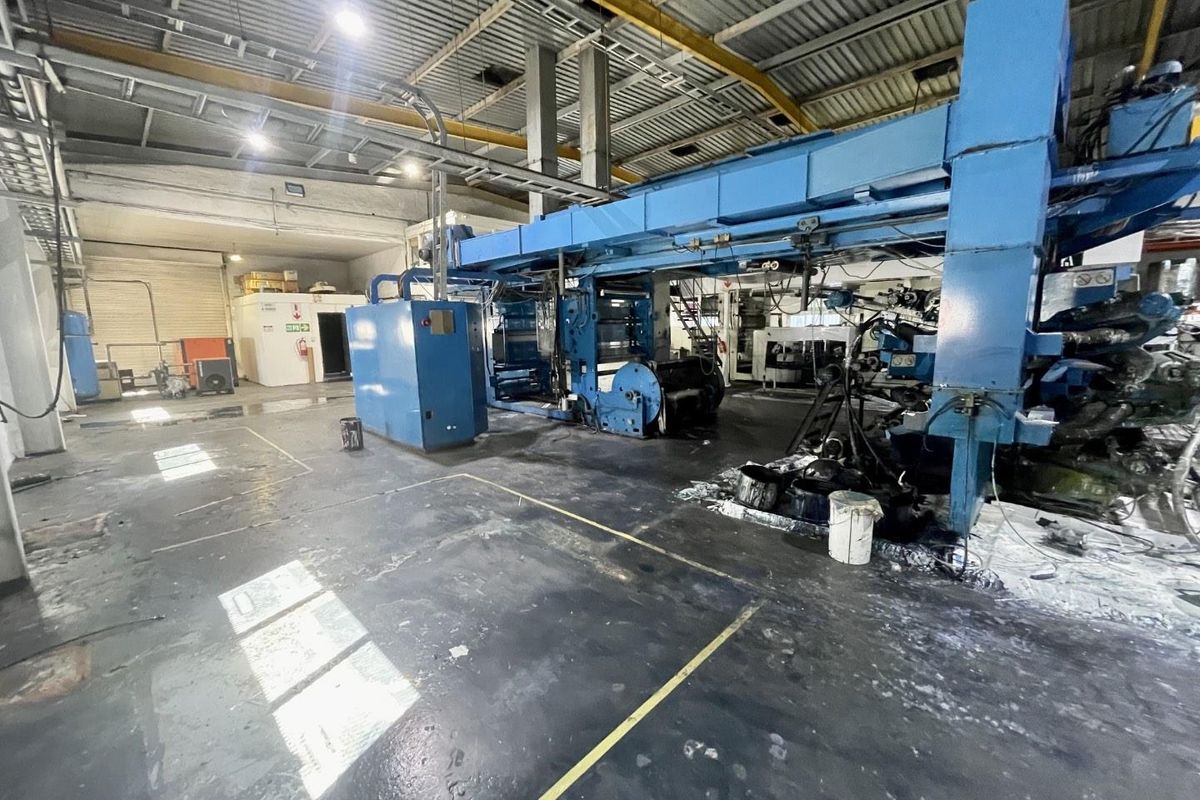 Industrial warehouse space featuring exposed steel roof structure, high-bay lighting, and heavy-duty industrial flooring suitable for manufacturing or storage operations.