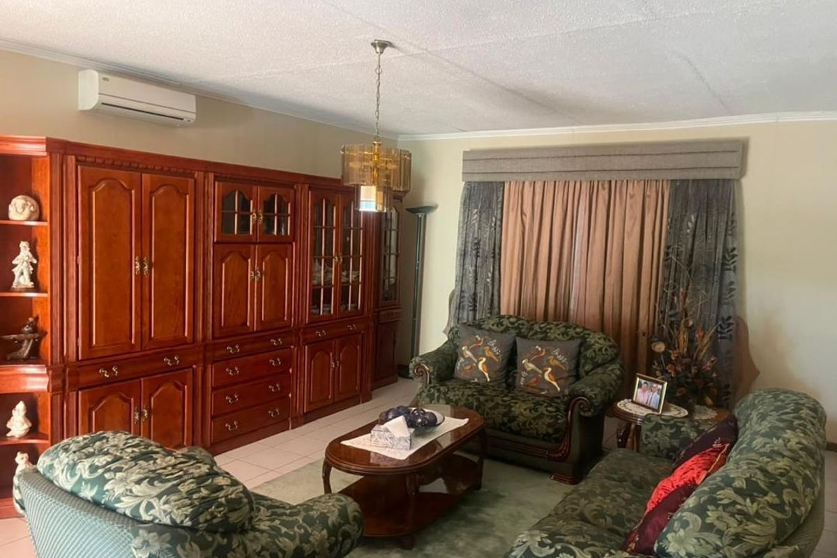A traditional living room featuring tiled flooring, a split-system air conditioner, and extensive built-in wooden cabinetry.