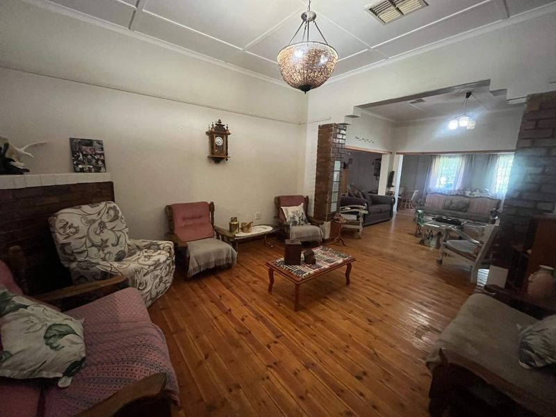 Spacious open-plan living area featuring polished timber flooring, exposed brick architectural elements, and a decorative ceiling with integrated lighting.