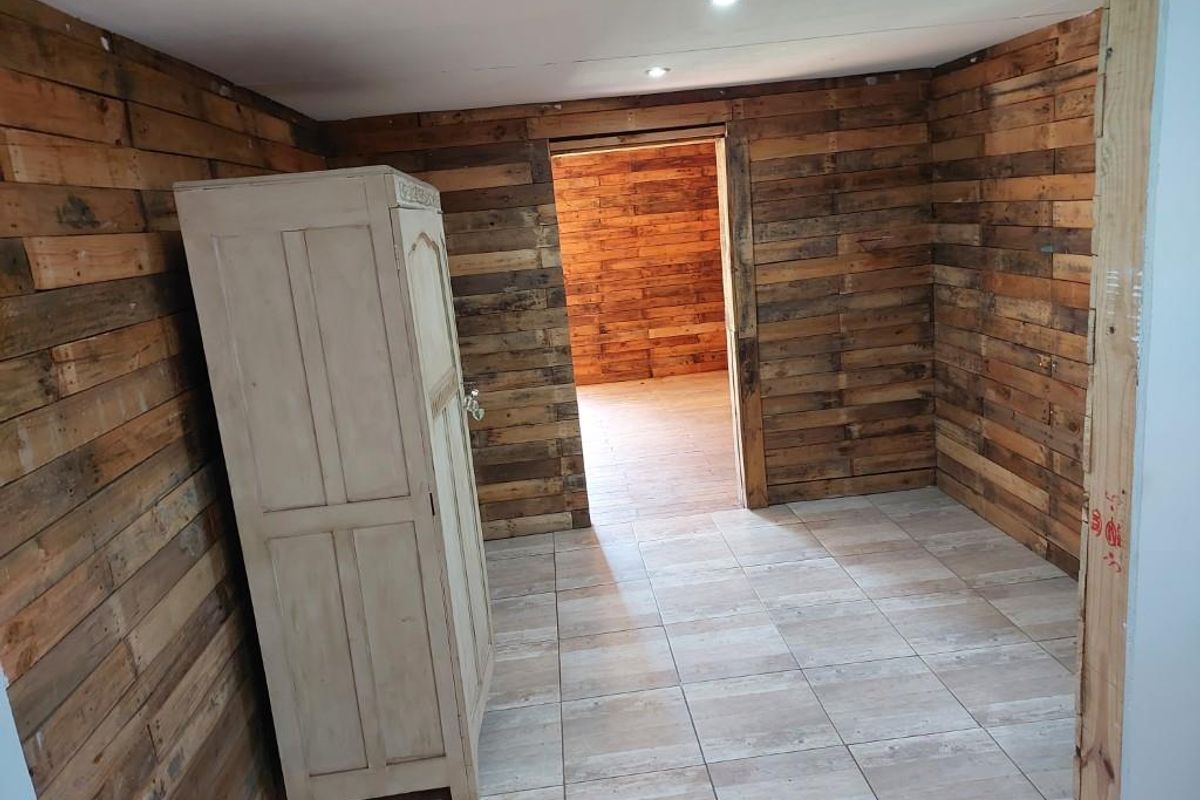 Bedroom featuring rustic reclaimed wood wall cladding and tiled flooring, with recessed lighting and an open doorway leading to an adjacent room.