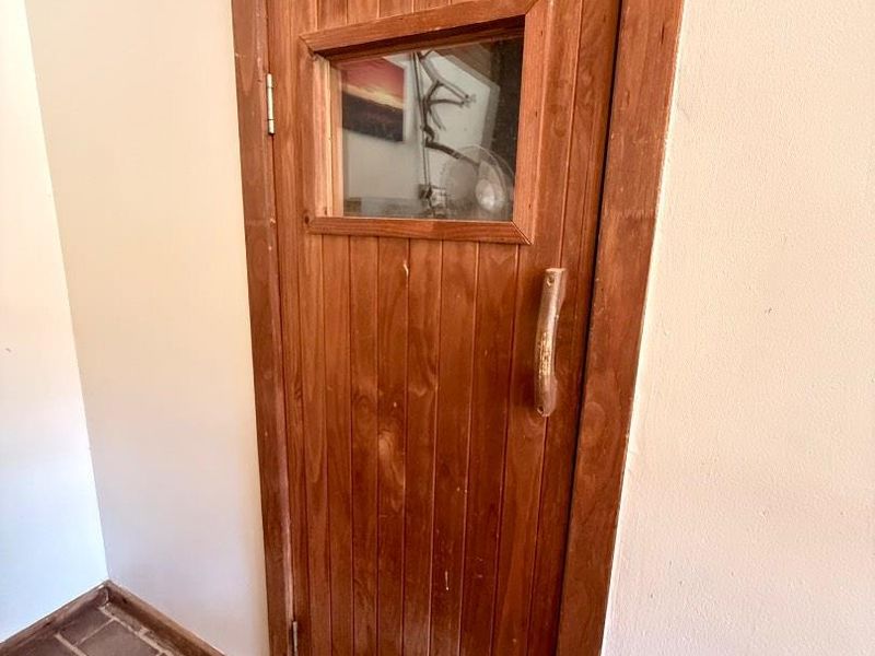 A dedicated sauna room featuring a timber door with a glass vision panel and traditional brick flooring.
