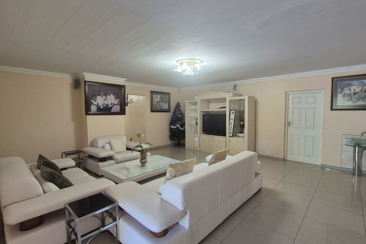Spacious living room featuring tiled flooring, crown molding, and a built-in entertainment unit.