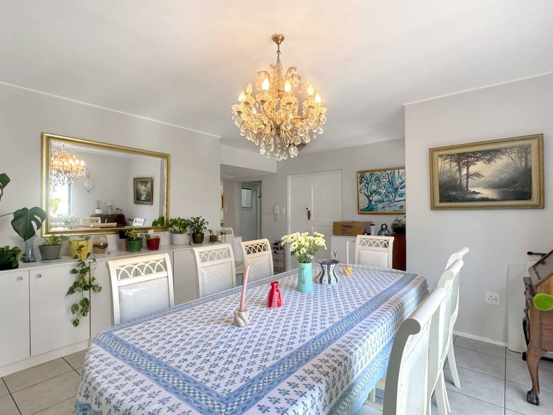 A well-maintained dining room featuring tiled flooring, a classic crystal chandelier, and built-in cabinetry providing ample storage space.