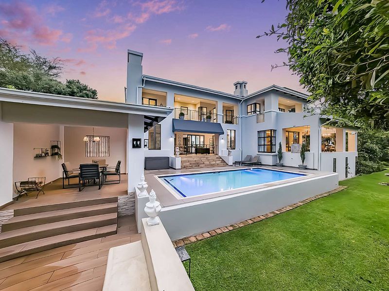 Stunning rear elevation featuring a swimming pool, covered patio area, elevated balconies, and well-maintained garden space, perfect for outdoor entertaining.