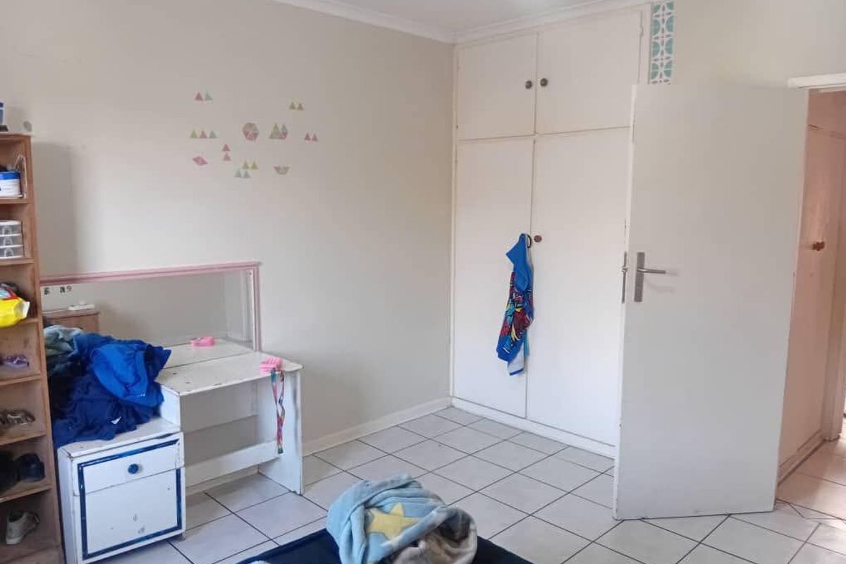 A bedroom featuring built-in cupboards with overhead storage and tiled flooring.