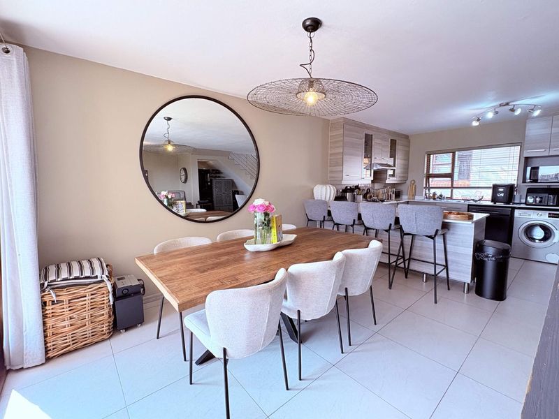 Open-plan living and dining area featuring a modern kitchen with island, tiled flooring, and contemporary pendant lighting.