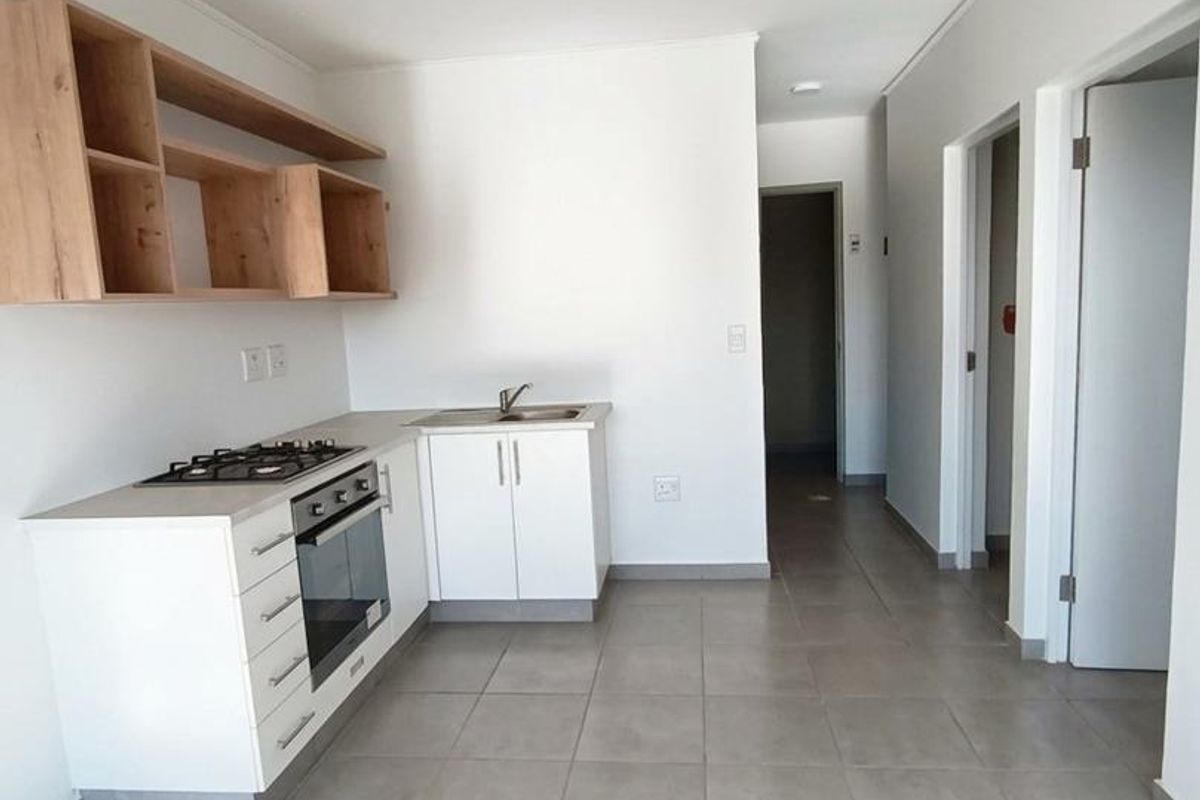 Modern kitchen featuring white cabinetry, gas hob, built-in oven, and open shelving, set against neutral tiled flooring in an open-plan layout.
