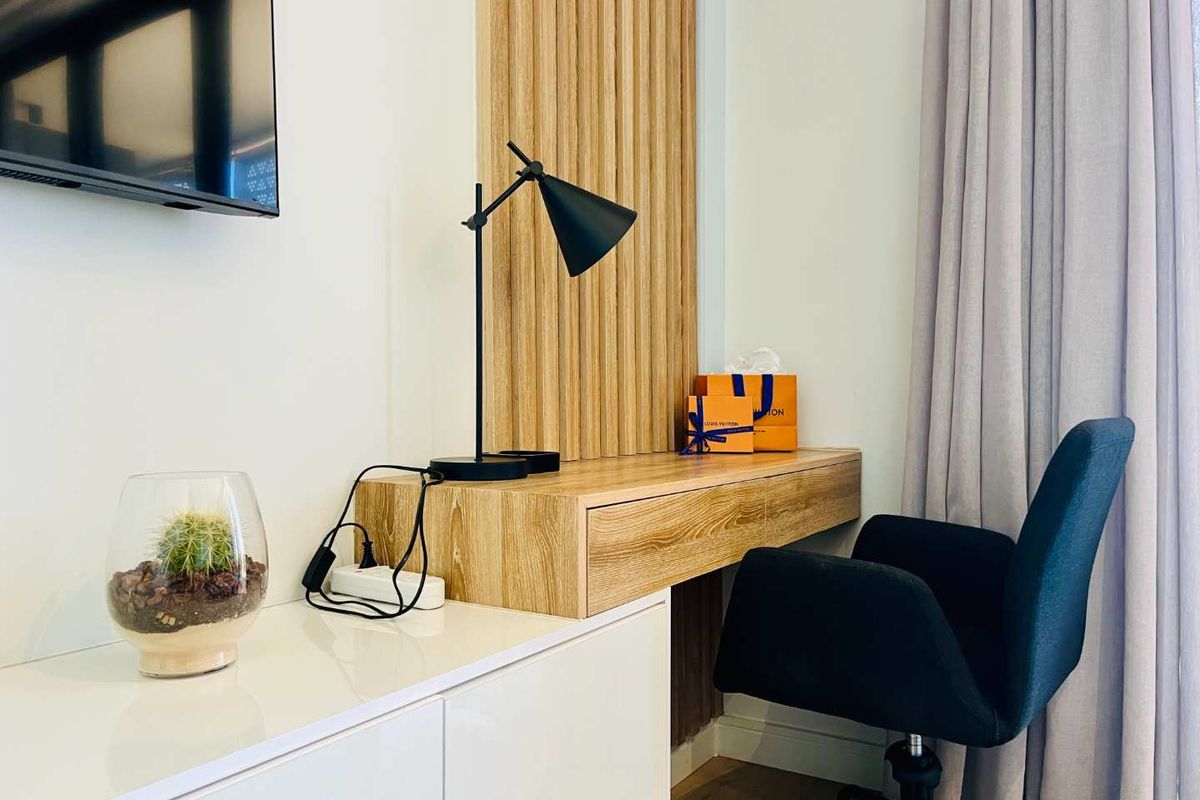 A modern bedroom workspace featuring a built-in floating timber desk with vertical slat wall paneling and integrated cabinetry.