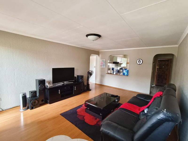 Spacious living room featuring laminate flooring, neutral textured walls, and a convenient pass-through window connecting to the kitchen area.