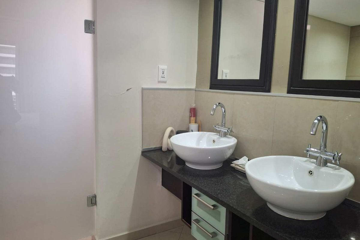 A functional bathroom featuring a double vanity with vessel sinks, granite countertop, built-in cabinetry, and wall-mounted mirrors.