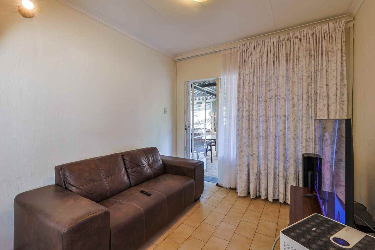 A living room featuring tiled flooring and a sliding glass door providing access to an outdoor patio area.