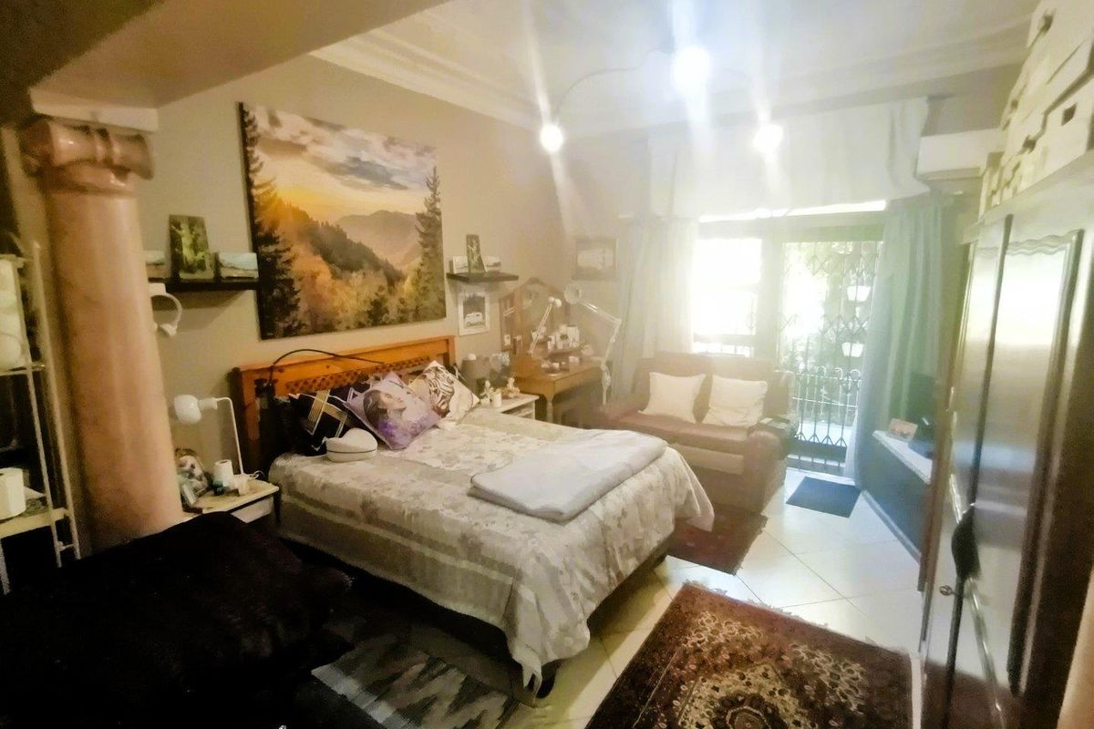 A bedroom featuring tiled flooring, a decorative column, and direct access to an outdoor patio area through a glass door.